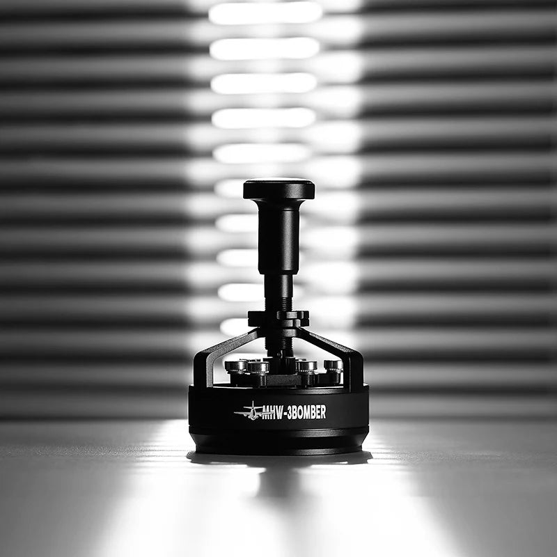 Centered against a blurred striped background, a black coffee tamper casts a shadow underneath. Branded with MHW-3BOMBER in white text, it emphasizes espresso precision and perfect grounds distribution, showcasing the MHW-3BOMBER YU Series Cyclone Needle Distributor WDT Tool.