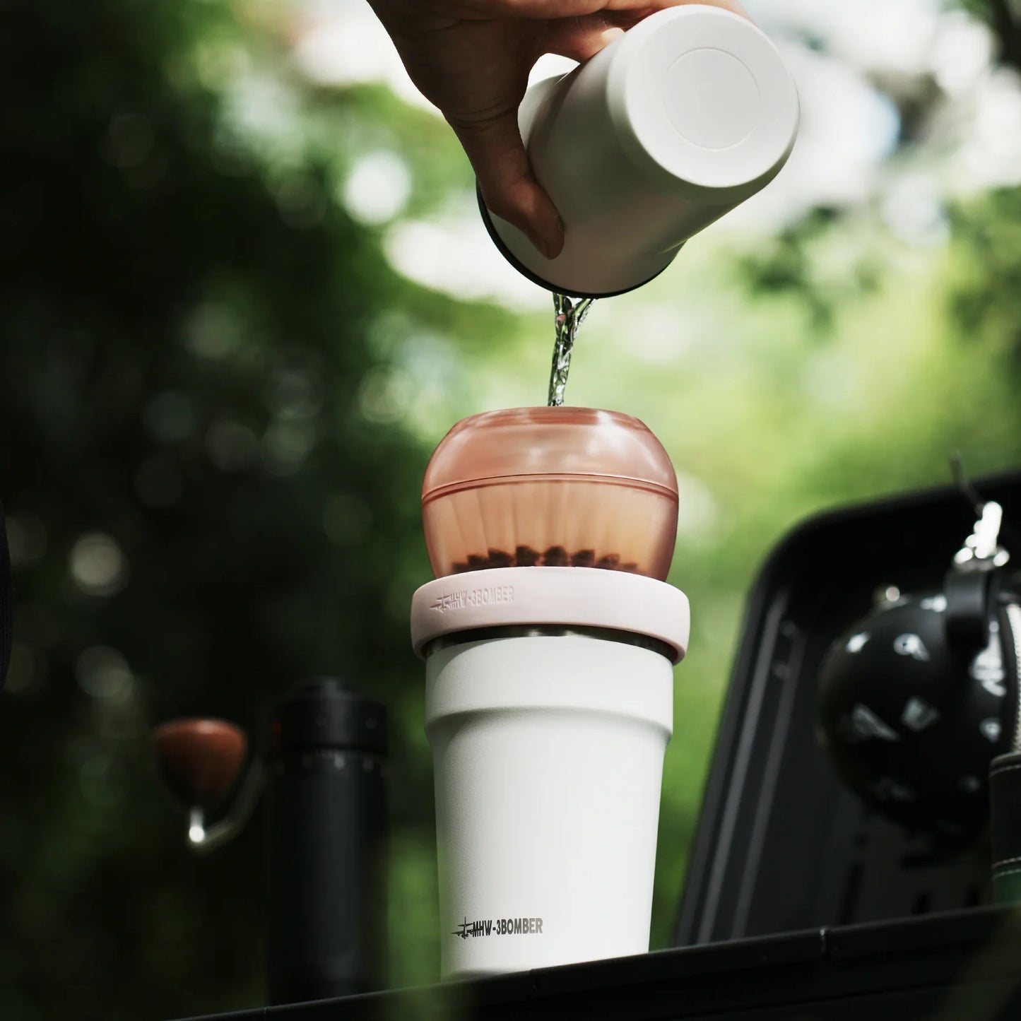 MHW-3BOMBER Eggonaut Dripper: Water pouring into pink pour-over brewer on a white cup. Travel coffee set.