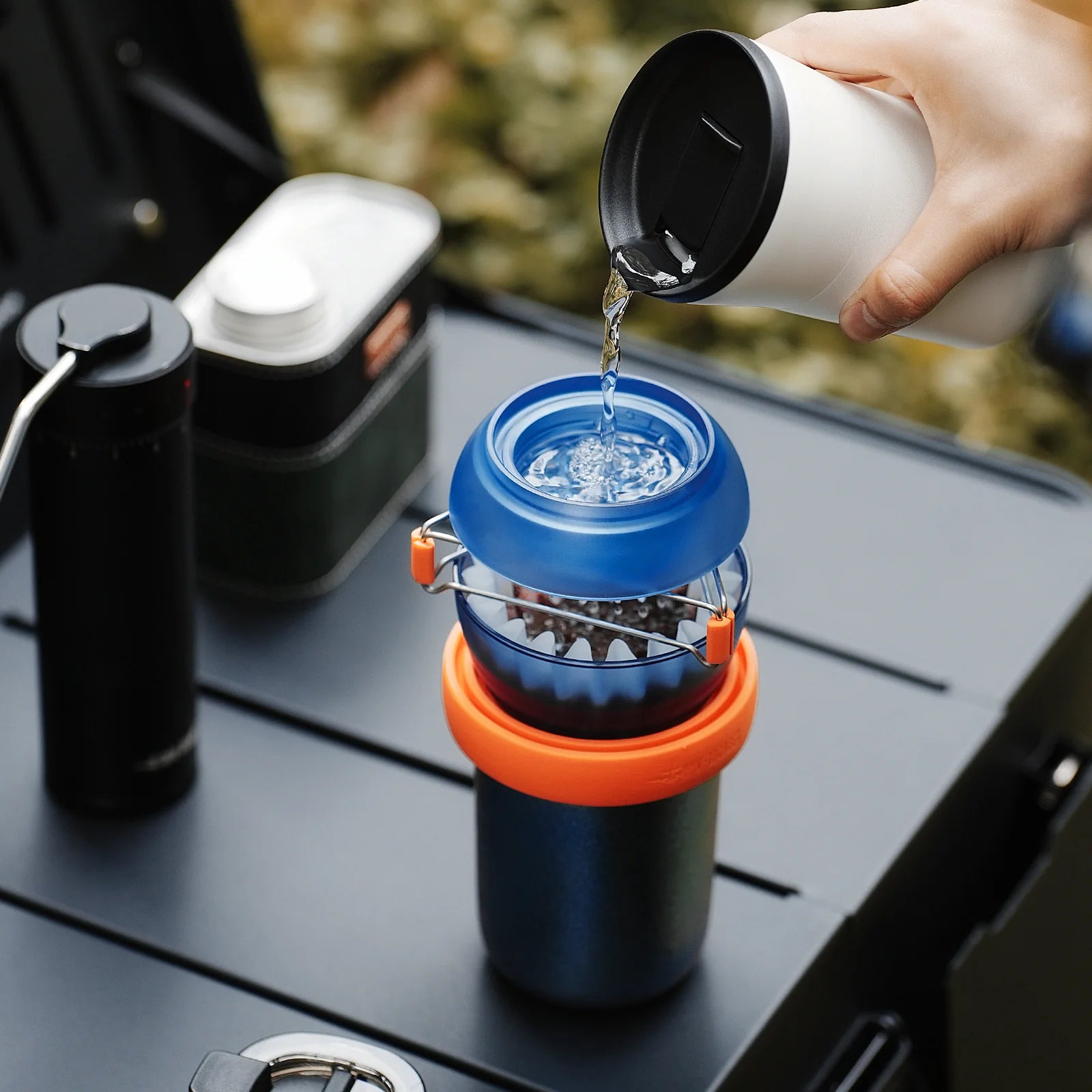 MHW-3BOMBER Eggonaut Dripper being used. Portable coffee brewer set with orange/blue accents. Water being poured in.