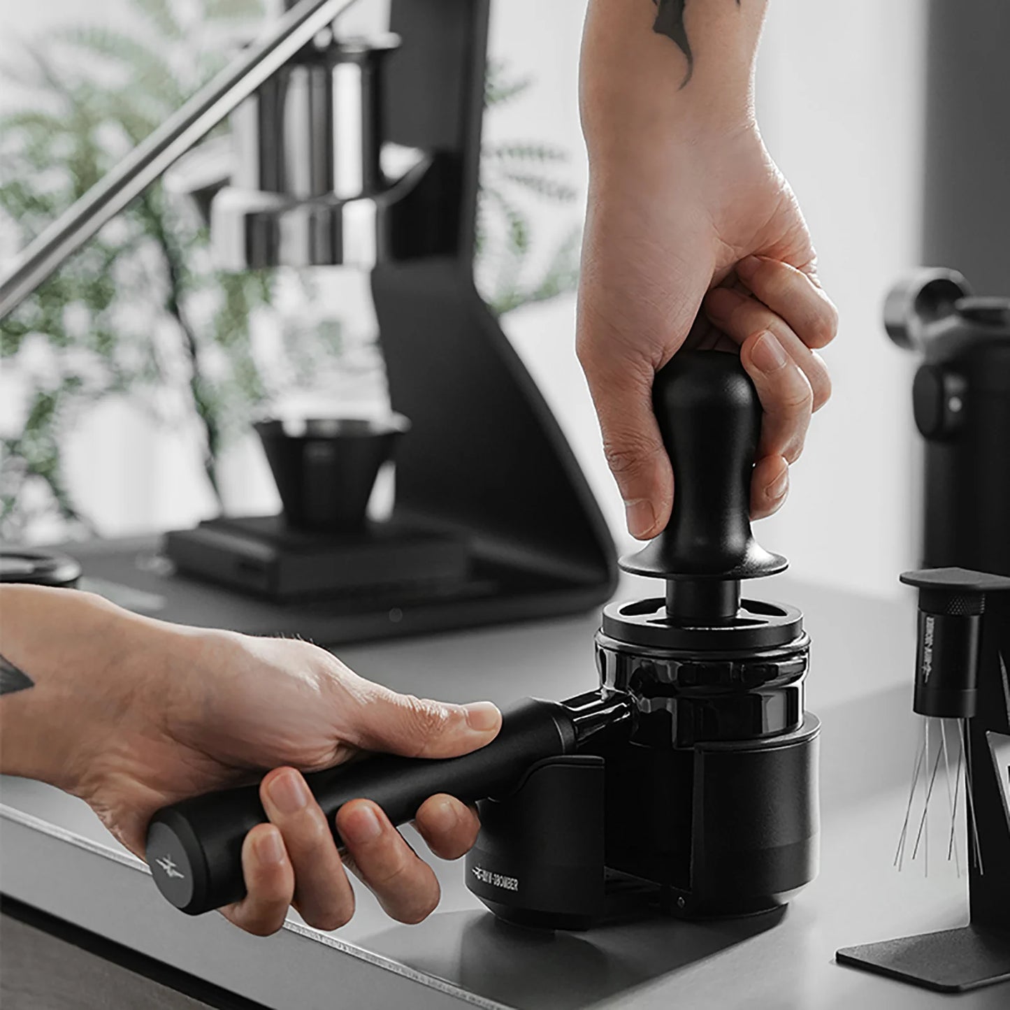 MHW-3BOMBER black portafilter and tamper being used on counter. Focus on espresso making tools.