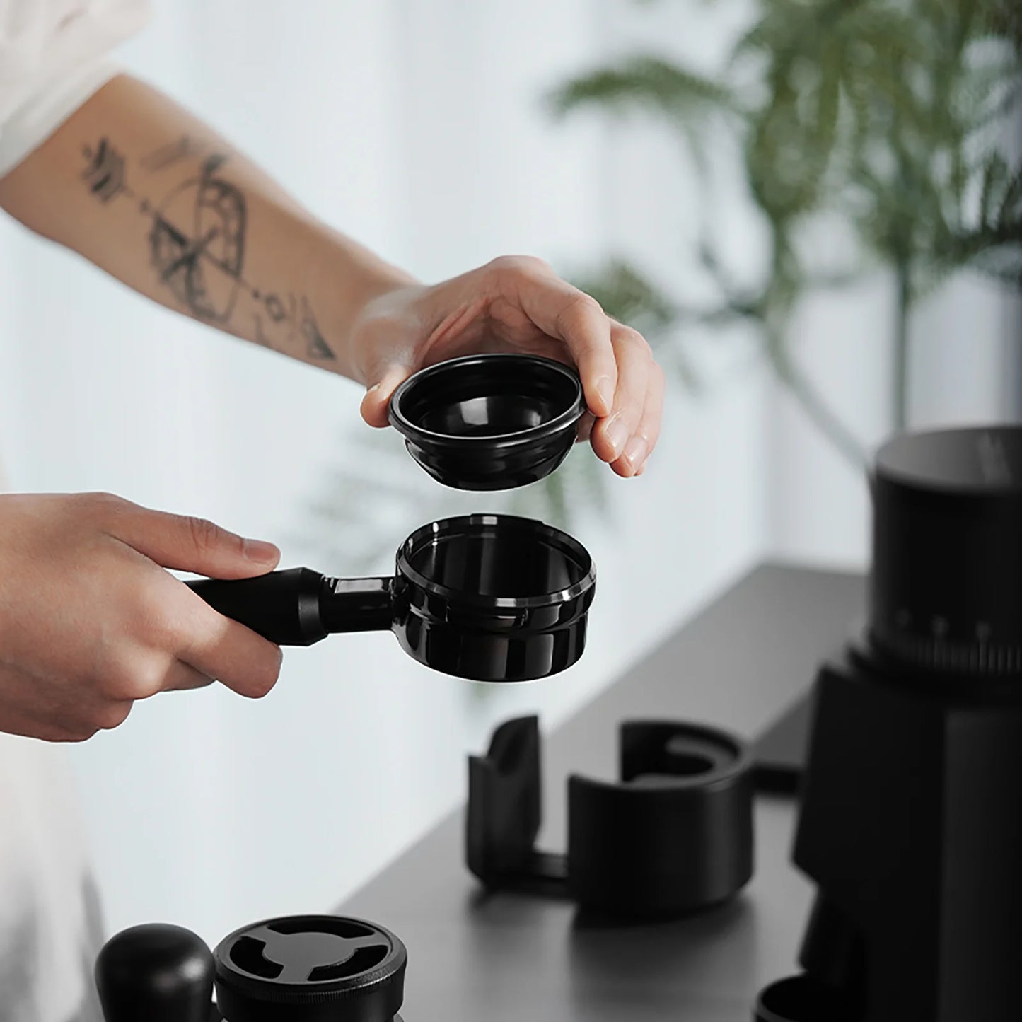 MHW-3BOMBER black bottomless portafilter with cup in use on kitchen counter.