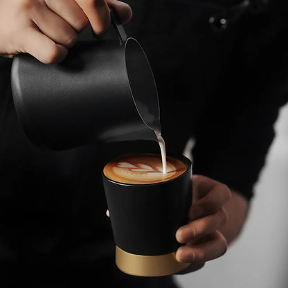 MHW-3BOMBER CERA Black ceramic cup being filled with milk; showcasing U-shaped design and color-blocking metal base.