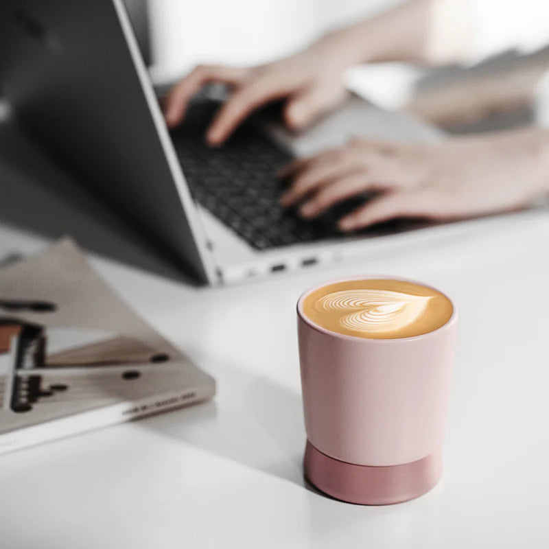 MHW-3BOMBER CERA pink ceramic coffee cup with latte art on a desk with laptop. Modern design coffee cup.