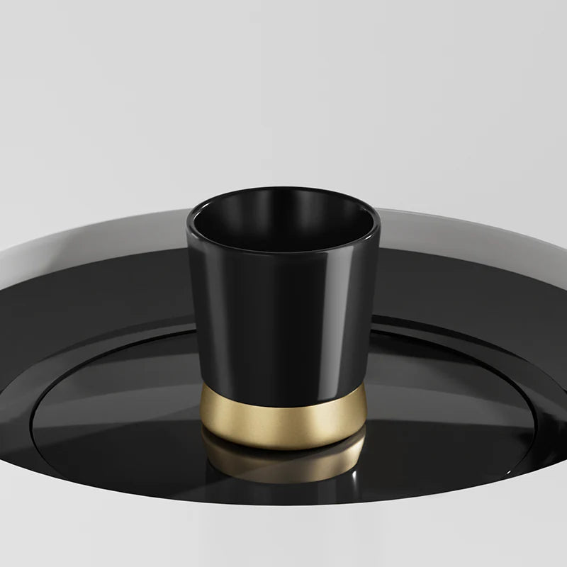 MHW-3BOMBER CERA black ceramic cup with a gold base on a matching black saucer. Modern design.