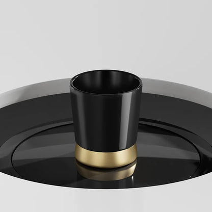 MHW-3BOMBER CERA black ceramic cup with a gold base on a matching black saucer. Modern design.