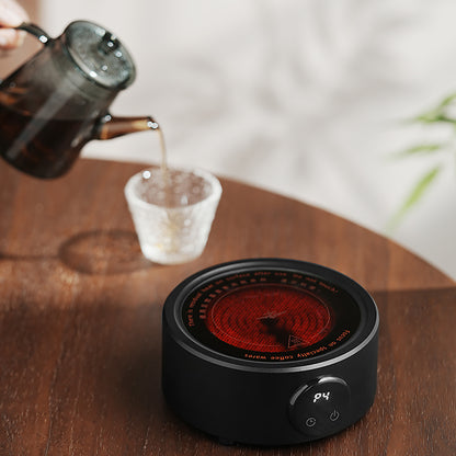 MHW-3BOMBER electric coffee heater in black. Hot plate shown, pouring water in glass. Compact, adjustable temp.