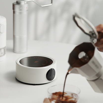 MHW-3BOMBER Electric Coffee Heater, white, with a moka pot pouring coffee. Compact, 800W stove with temperature control.