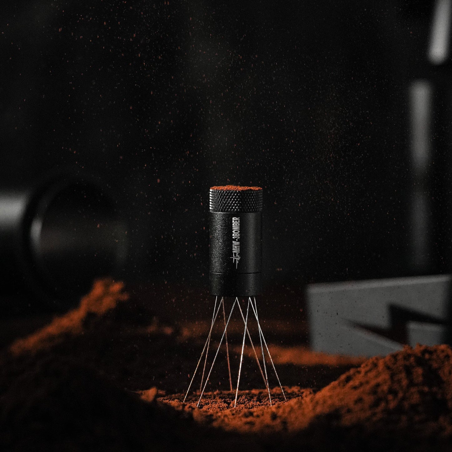 The MHW-3BOMBER Lightning Needle Distributor WDT Tool 2.0, a black cylindrical device on thin metal legs, resembles a magnetic stand amid brown dust in dim lighting. Dust floats around, creating a dynamic and mysterious ambiance.