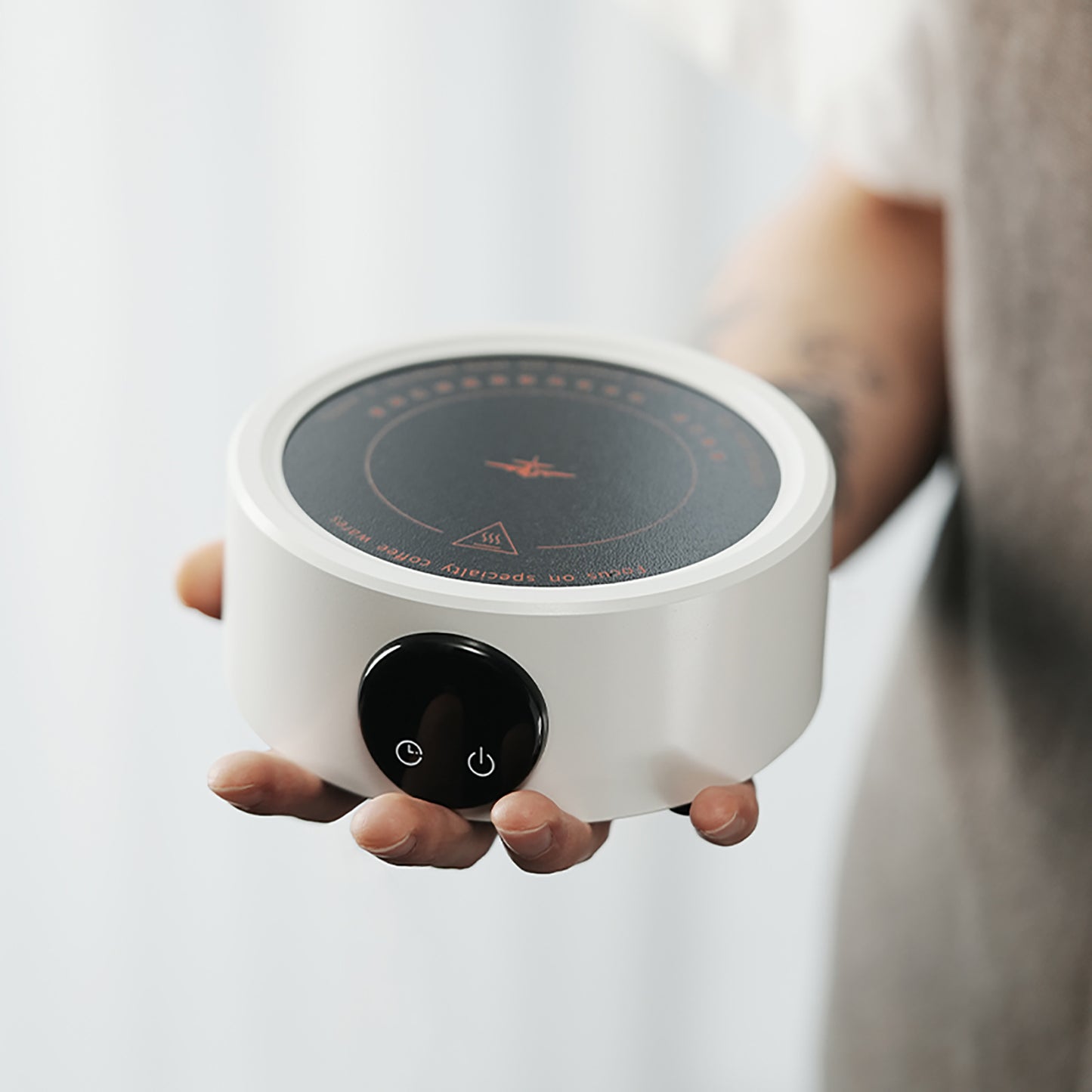 MHW-3BOMBER white mini electric coffee heater. Compact, round design with black heating plate and power button. Held in hand.