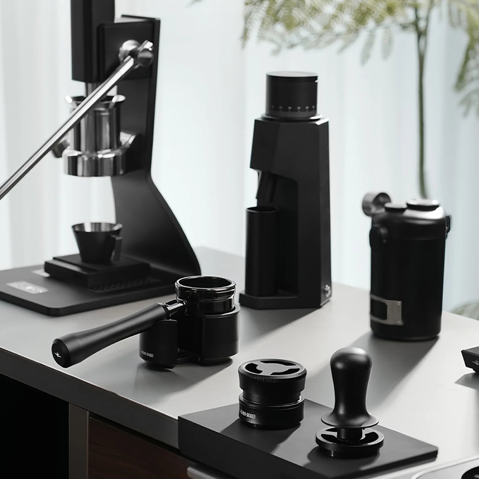 MHW-3BOMBER black espresso setup with manual lever machine, grinder, portafilter, tamper, and accessories.