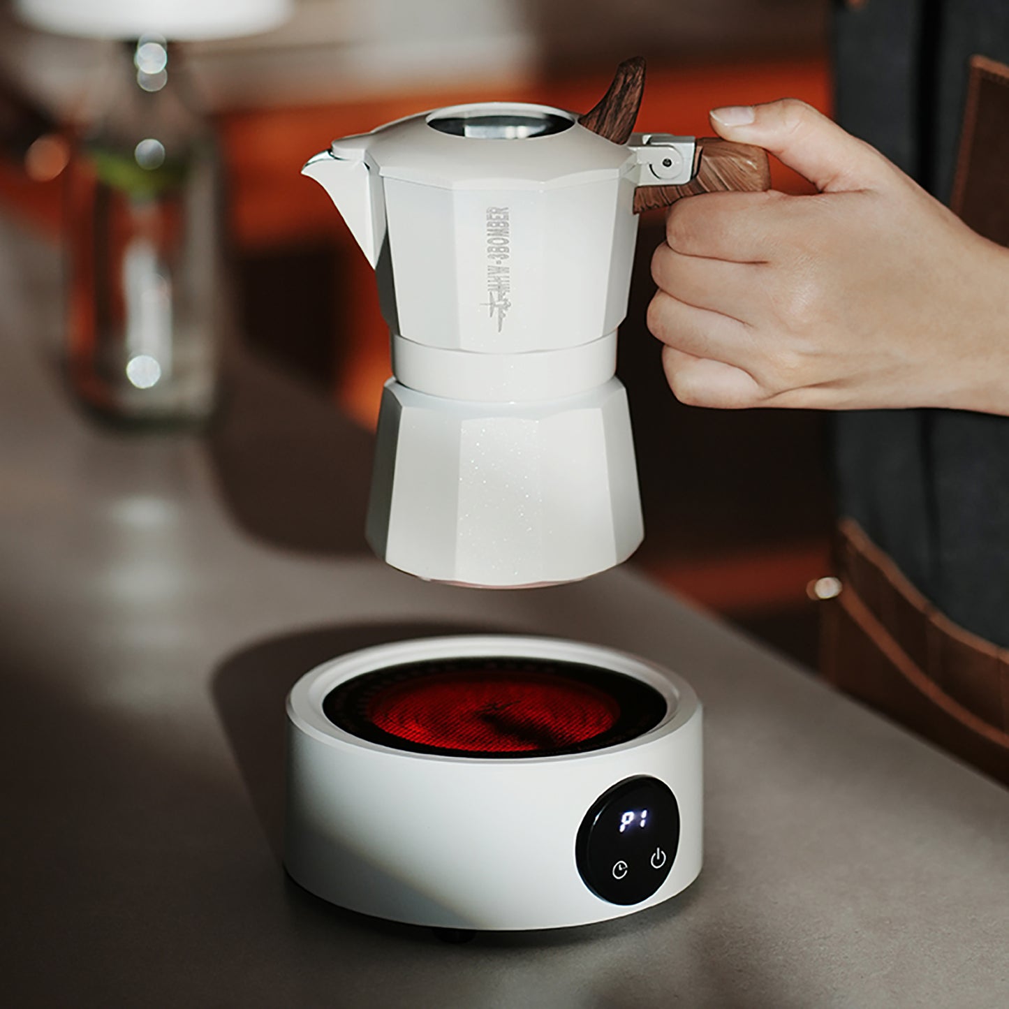 MHW-3BOMBER white Moka pot with wood handle on electric coffee heater. Brewing coffee. 