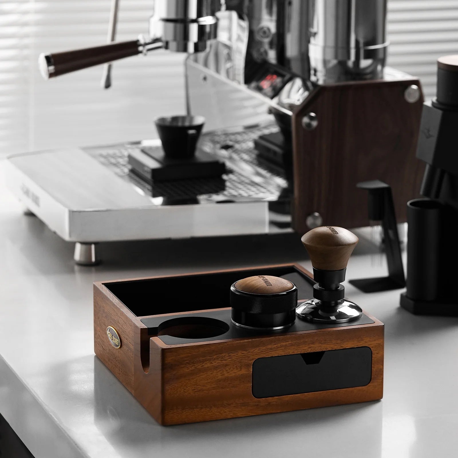 MHW-3BOMBER espresso knock box, walnut wood with black drawer, tamper and coffee distributor on counter. 