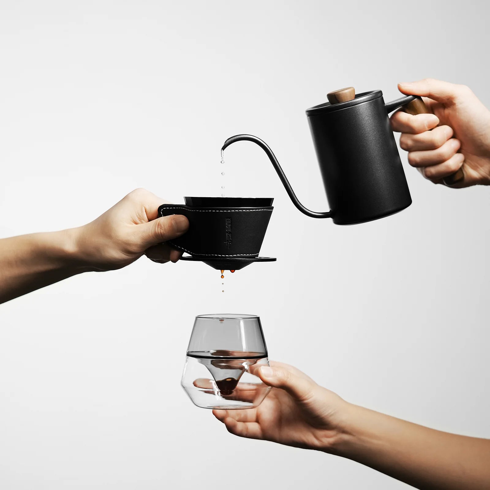 MHW-3BOMBER black coffee dripper pour-over set being used. Kettle pouring into dripper over geometric glass cup.