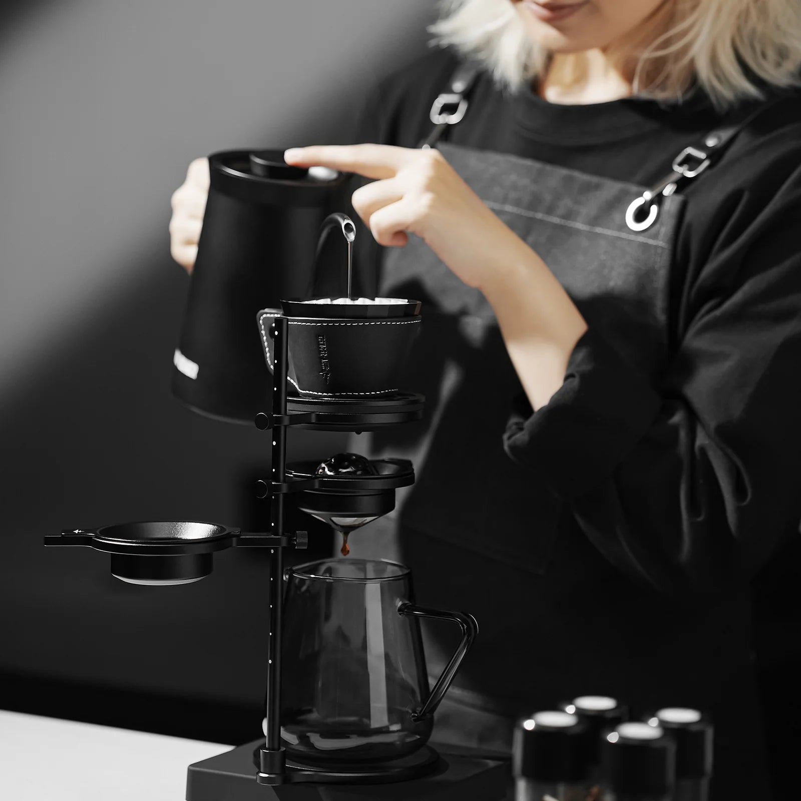 MHW-3BOMBER black pour-over coffee dripper setup with kettle and glass server, in use.