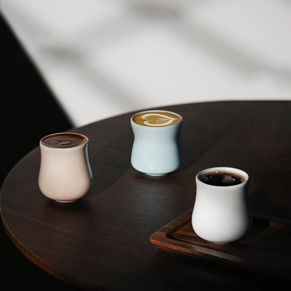 MHW-3BOMBER Aura cups: ceramic, unique shapes, pink, blue & white, filled w/ coffee on wood table. 