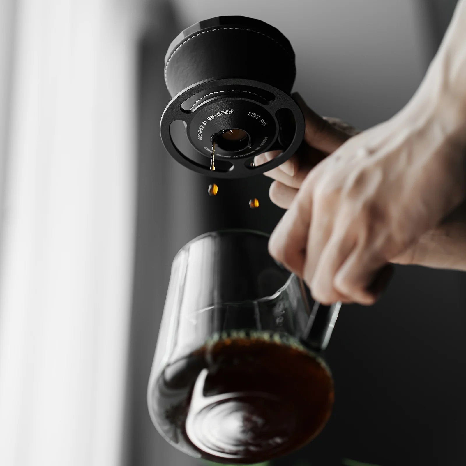 MHW-3BOMBER Meteorite Dripper in use. Black metal, unique rib design. Pour-over coffee brewing in glass. 