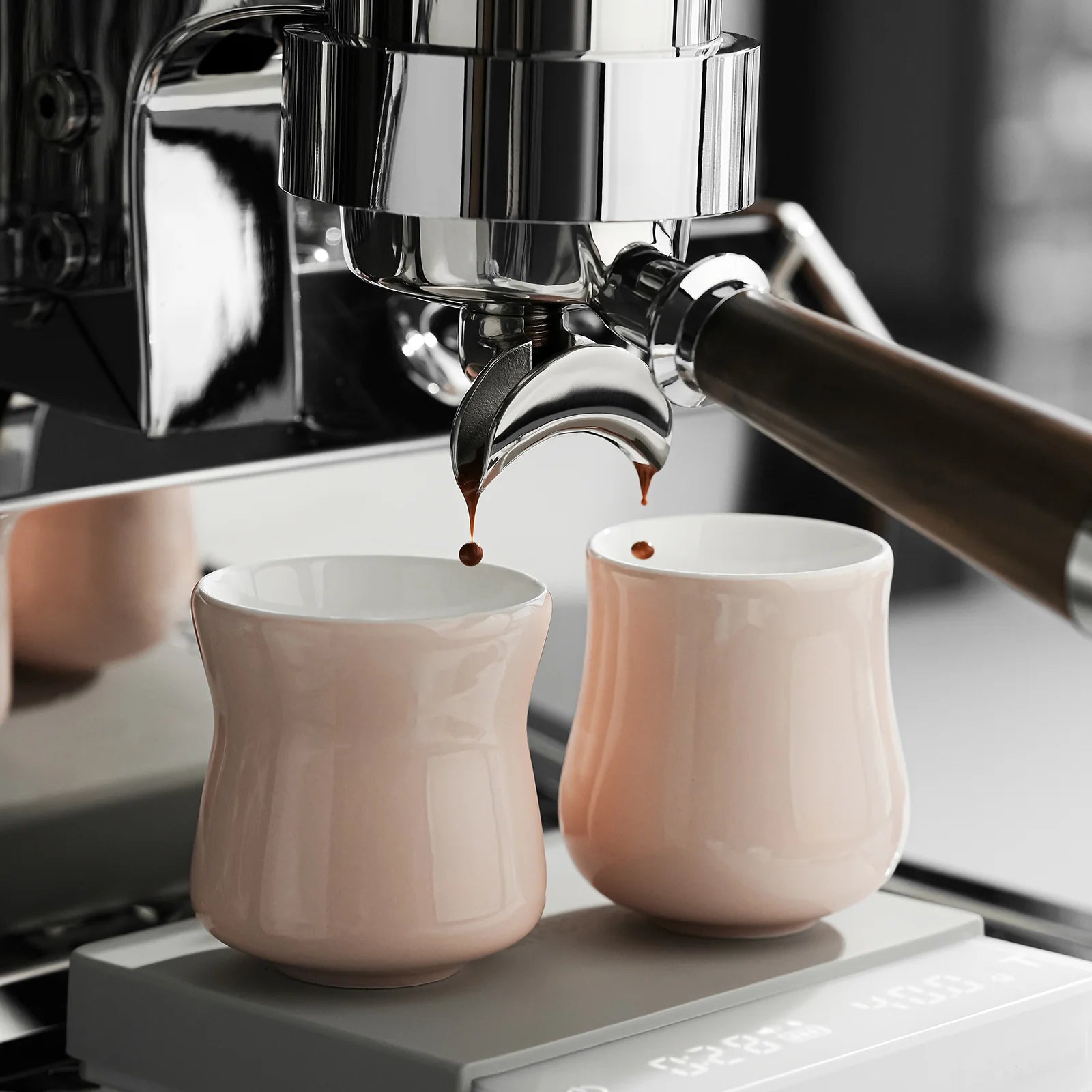 MHW-3BOMBER Aura pink ceramic cups being filled with espresso. Dual-cup design visible.