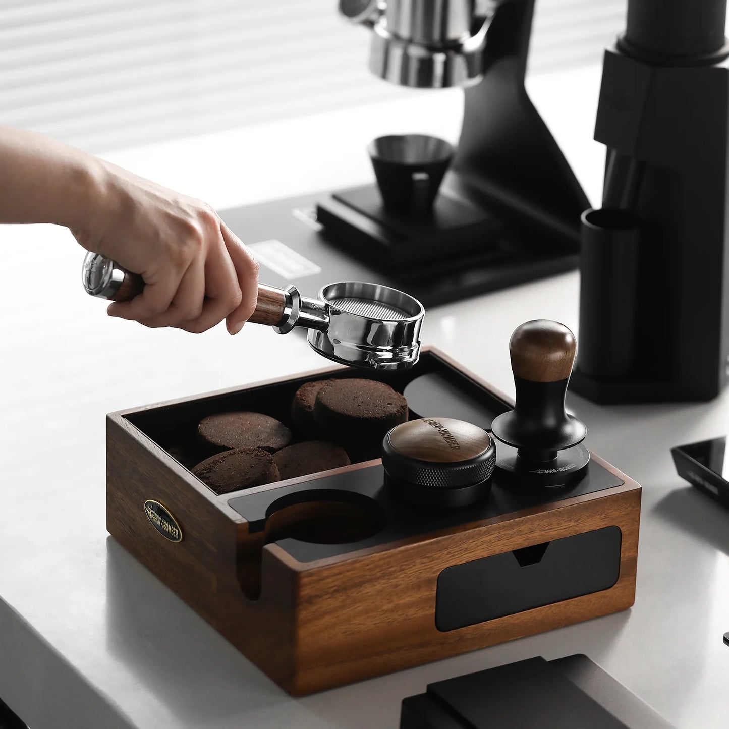 MHW-3BOMBER knock box station with portafilter and tamper, walnut wood finish. Espresso making on counter.