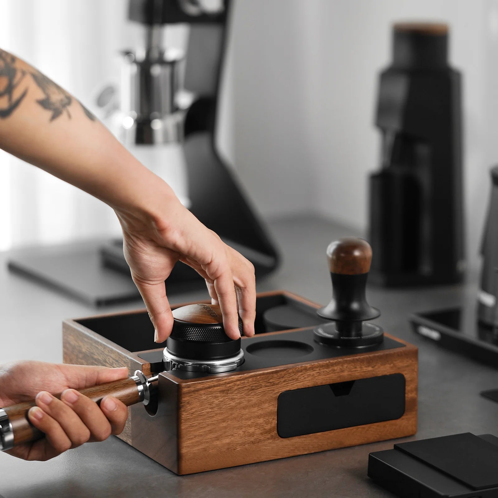 MHW-3BOMBER espresso knock box & tamping station. Wood with black accents, holding portafilter. Coffee tools shown.