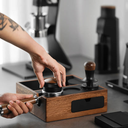 MHW-3BOMBER espresso knock box & tamping station. Wood with black accents, holding portafilter. Coffee tools shown.